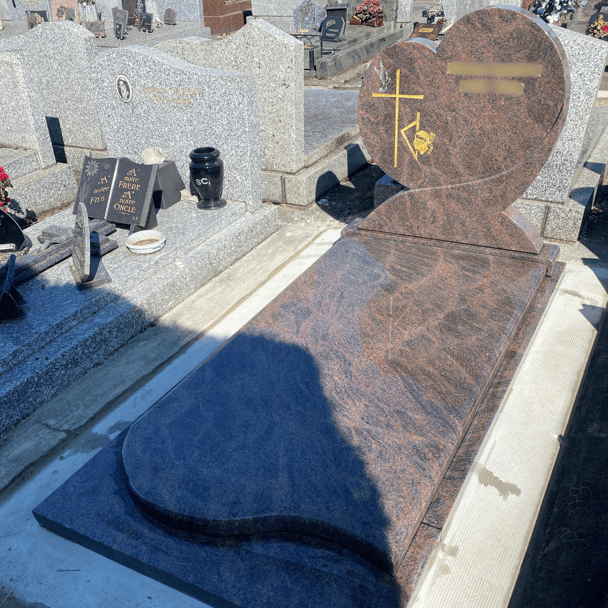 Monument funéraire en granit brun avec stèle en forme de cœur et croix dorée, posé au cimetière